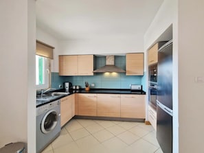 A compact kitchen with a washing machine, a built-in oven, and a stainless steel refrigerator. - Sunny 1-Bedroom Apartment Island Retreat with Pool Views at Vila Verde Resort (Sal)