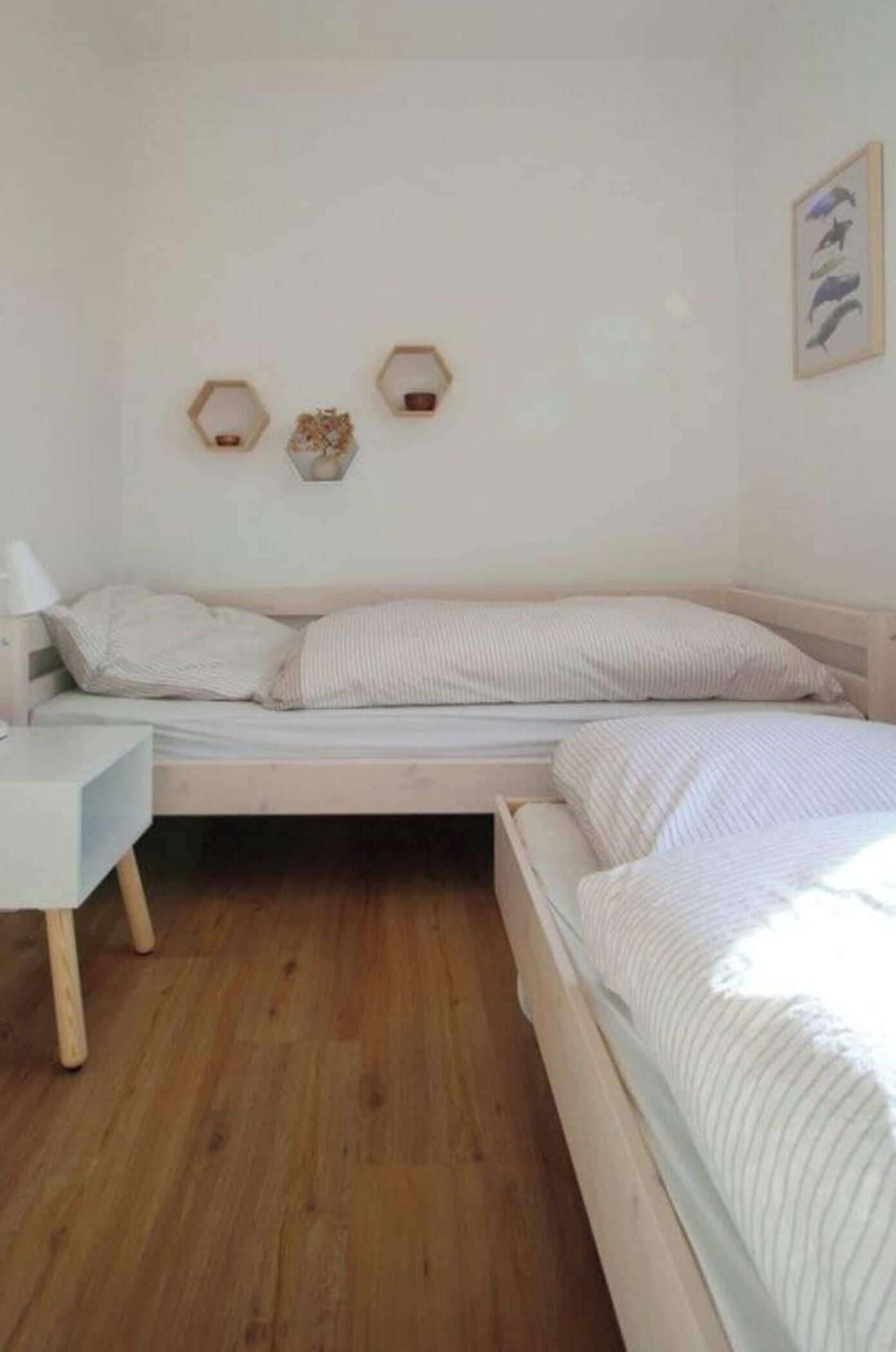 Un dormitorio con una cama de madera, una mesita de noche y dos repisas hexagonales decoradas con objetos decorativos.
