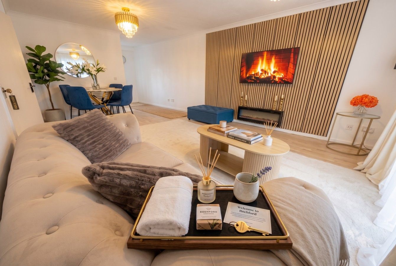 A modern hotel room with a large bed, a television, a fireplace, and a dining area.