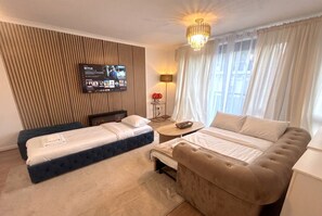 A hotel room with a bed, a sofa, a TV mounted on the wall, and a lamp. - 2-Bed Flat Sleeps 6 · Balcony · Walk to Earl`s Court Tube (Greater London)