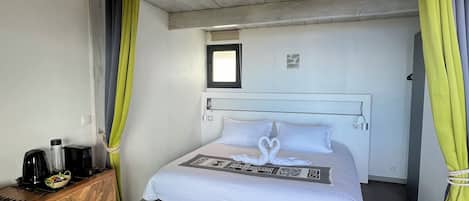Une chambre à coucher avec un lit, une commode en bois, une fenêtre et un luminaire au plafond.