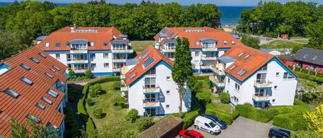 Un ensemble résidentiel composé de plusieurs immeubles à deux étages, chacun ayant un toit recouvert de tuiles rouges et doté de balcons.