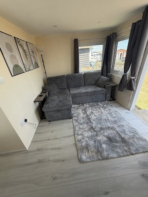Una sala de estar moderna con un sofá seccional gris, una alfombra gris suave y un ventanal con cortinas.