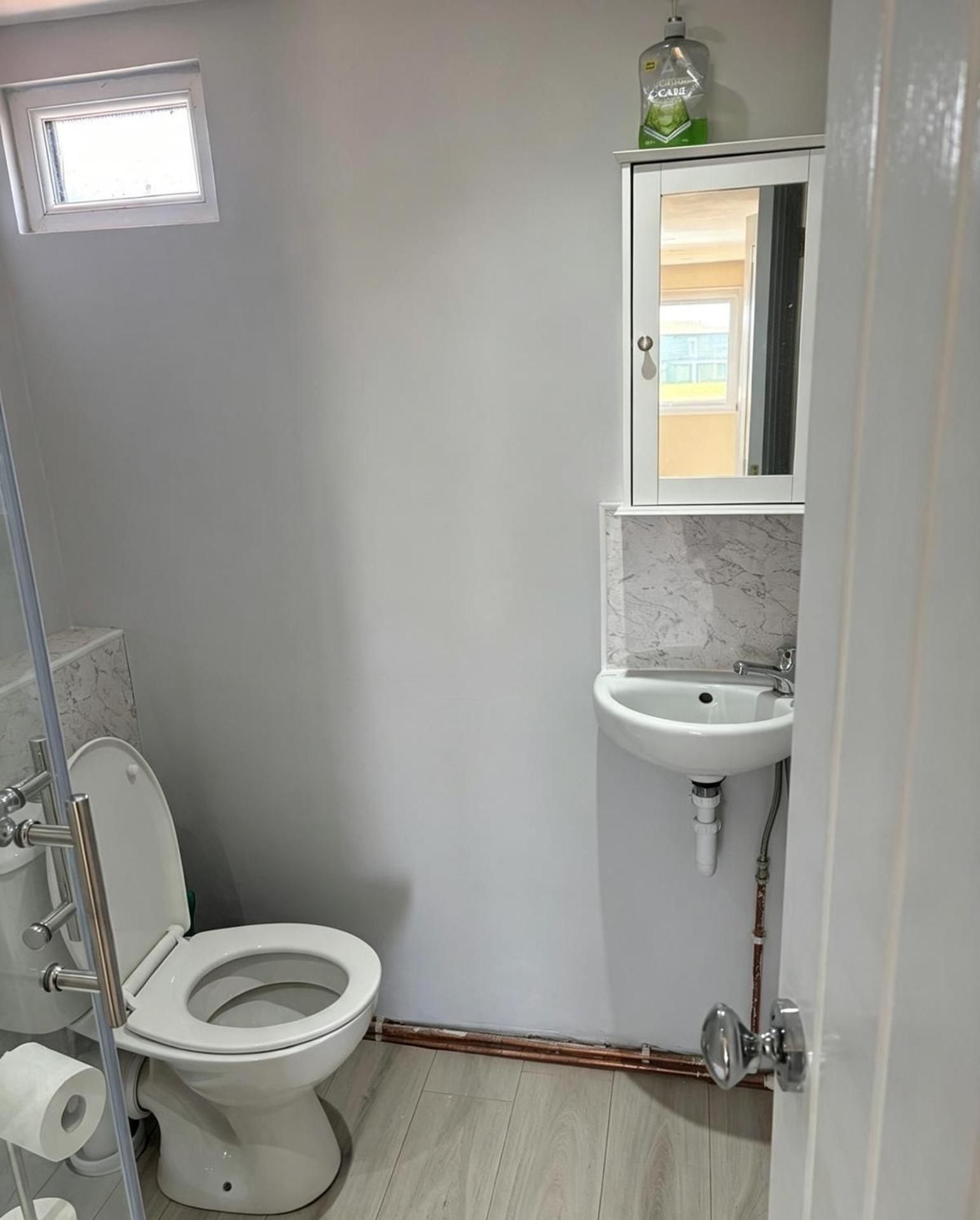 A small bathroom with a toilet, a sink, and a mirror.