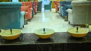 A hotel lobby with rows of armchairs and a reception desk with three water fountains.