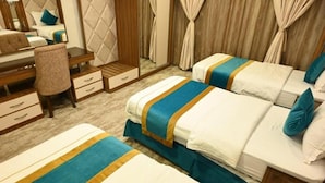 Hotellihuone, jossa on kaksi sänkyä, työpöytä ja peili.