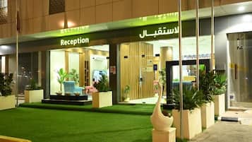 A hotel reception with a green carpet and potted plants.