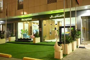 A hotel reception with a green carpet and potted plants. - Jawharat Al Sarat for hotel apartments (Al-Amjad District)
