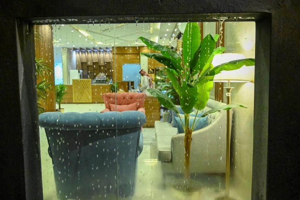 Un hall de hotel con zona de estar, mostrador de recepción y una planta.