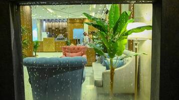 Un hall de hotel con zona de estar, mostrador de recepción y una planta.