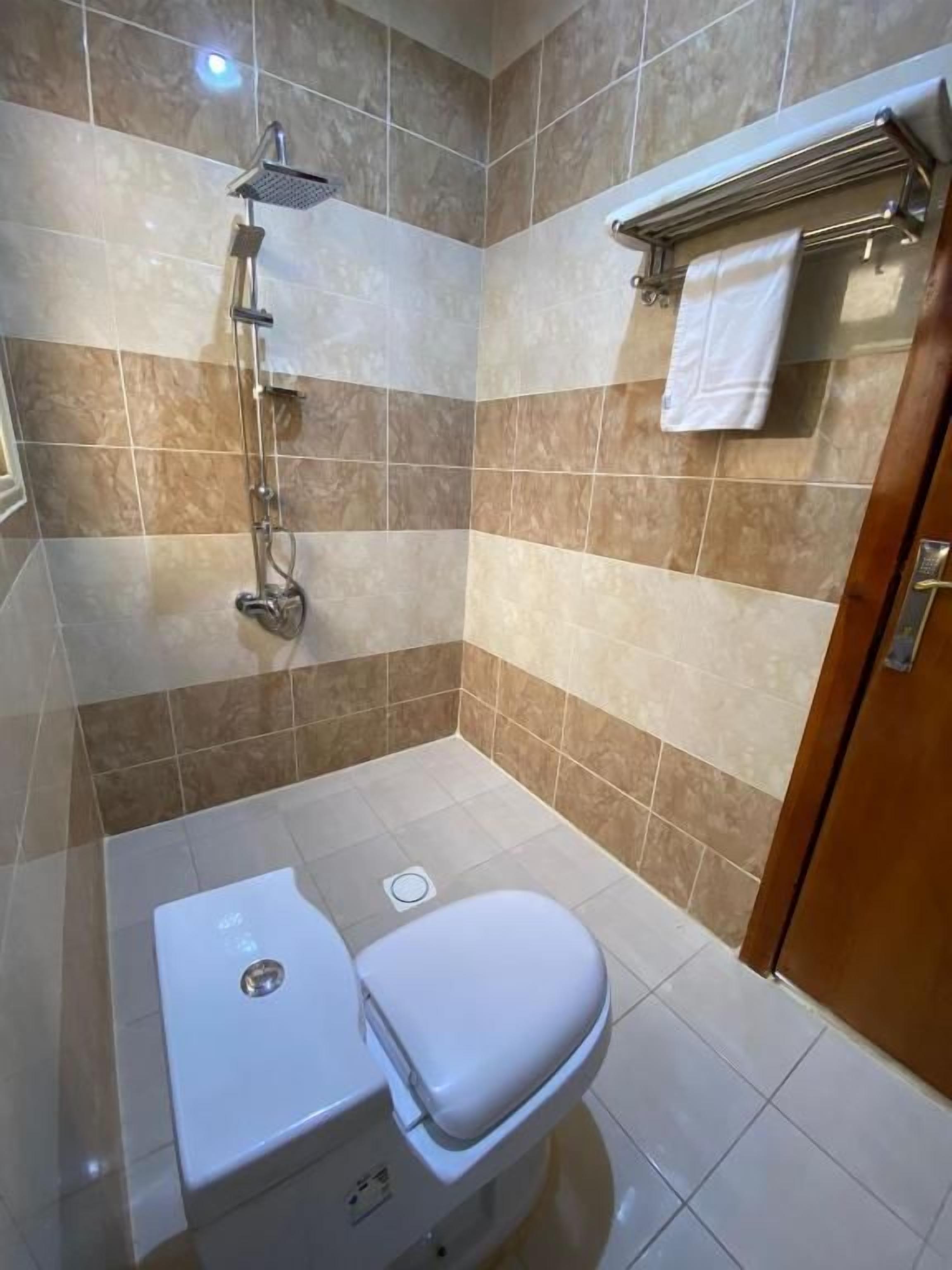 Un baño con ducha, inodoro y perchero para toallas.