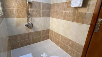 Un baño con ducha, inodoro y perchero para toallas.