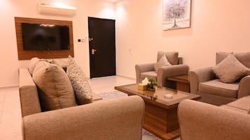 A living room with sofas, a coffee table, a flat-screen TV, and a door.