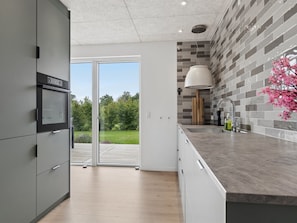 A modern kitchen with a built-in oven, a large window, and a view of the outdoors. - "Ragmar" - 525m from the sea by Interhome (Føllenslev)