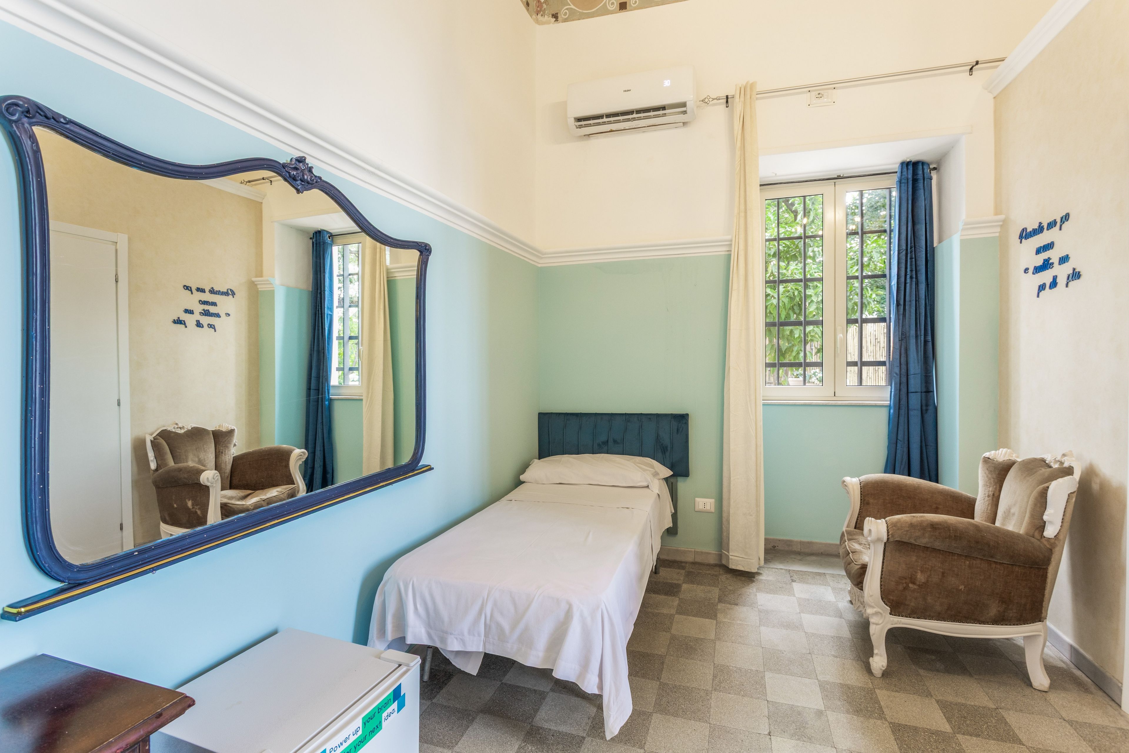 A room with a bed, a chair, a dresser, a mirror, and a window with curtains.