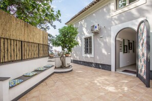 A courtyard with a bamboo fence, a small tree, and a tiled floor. - Stanze Letterarie - 'Giovanni Verga' (Catania)