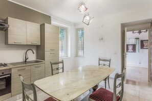 A modern kitchen with a marble countertop, stainless steel appliances, and a dining area with a marble table and chairs. - Stanze Letterarie - 'Giovanni Verga' (Catania)