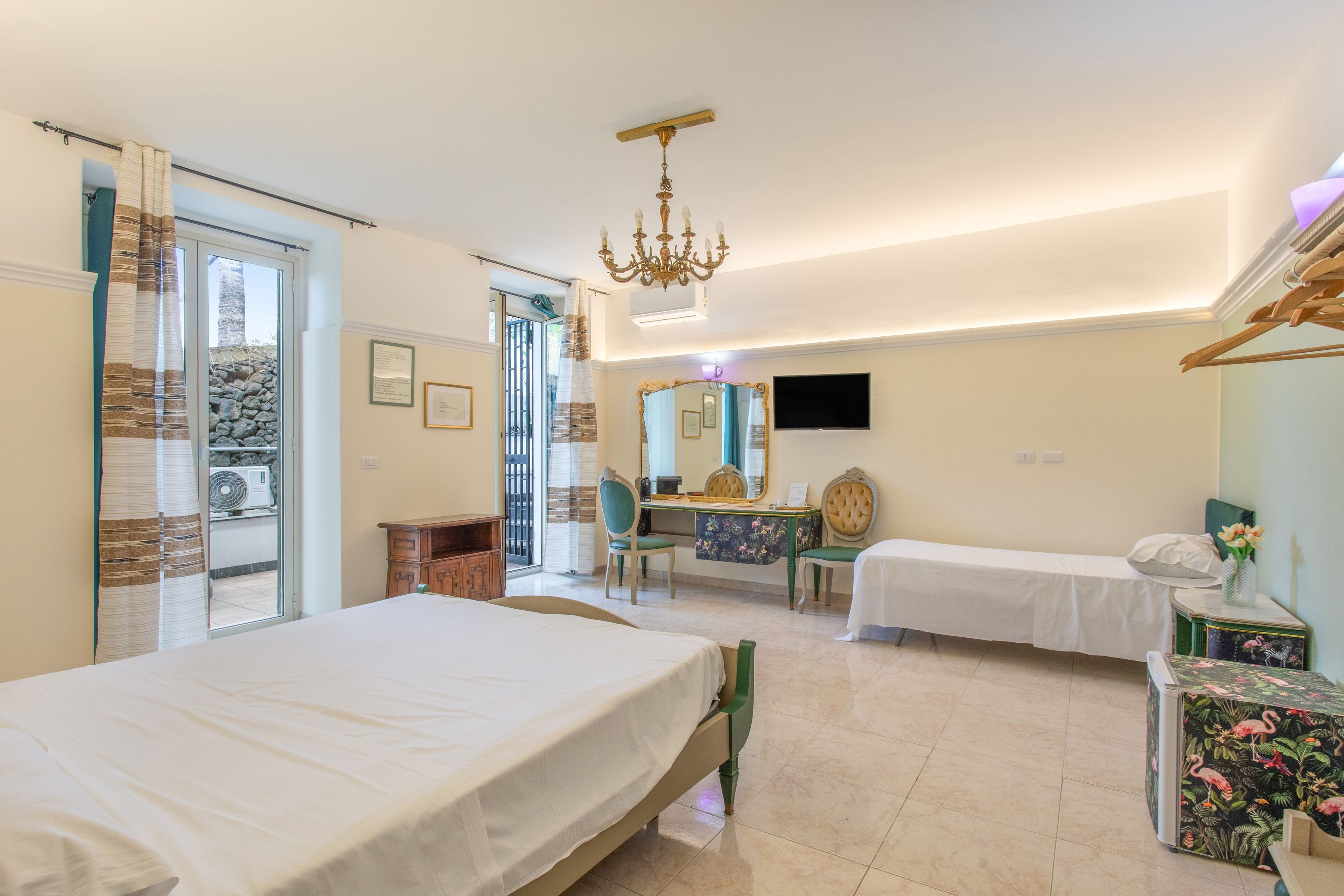 Une chambre d’hôtel avec deux lits, un bureau, une chaise, une télévision et un lustre.