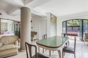A spacious dining area with a glass-top table, surrounded by chairs, and a large column. - Stanze Letterarie -  'Mario Grasso'  (Catania)