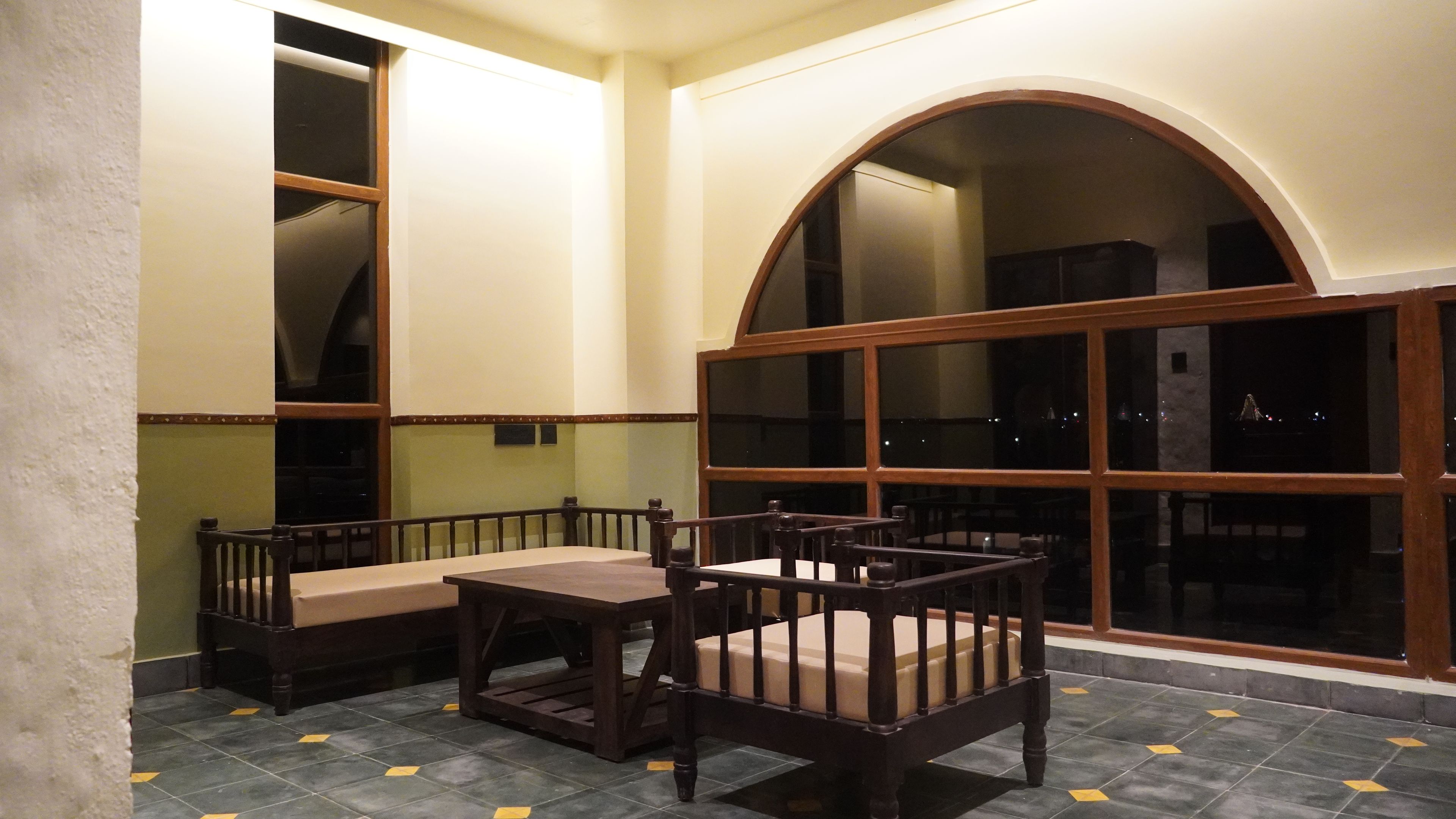 Una habitación con una mesa de comedor y sillas, un amplio ventanal de arco y suelo de baldosas.