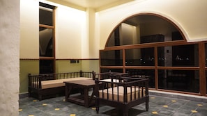 Una habitación con una mesa de comedor y sillas, un amplio ventanal de arco y suelo de baldosas.