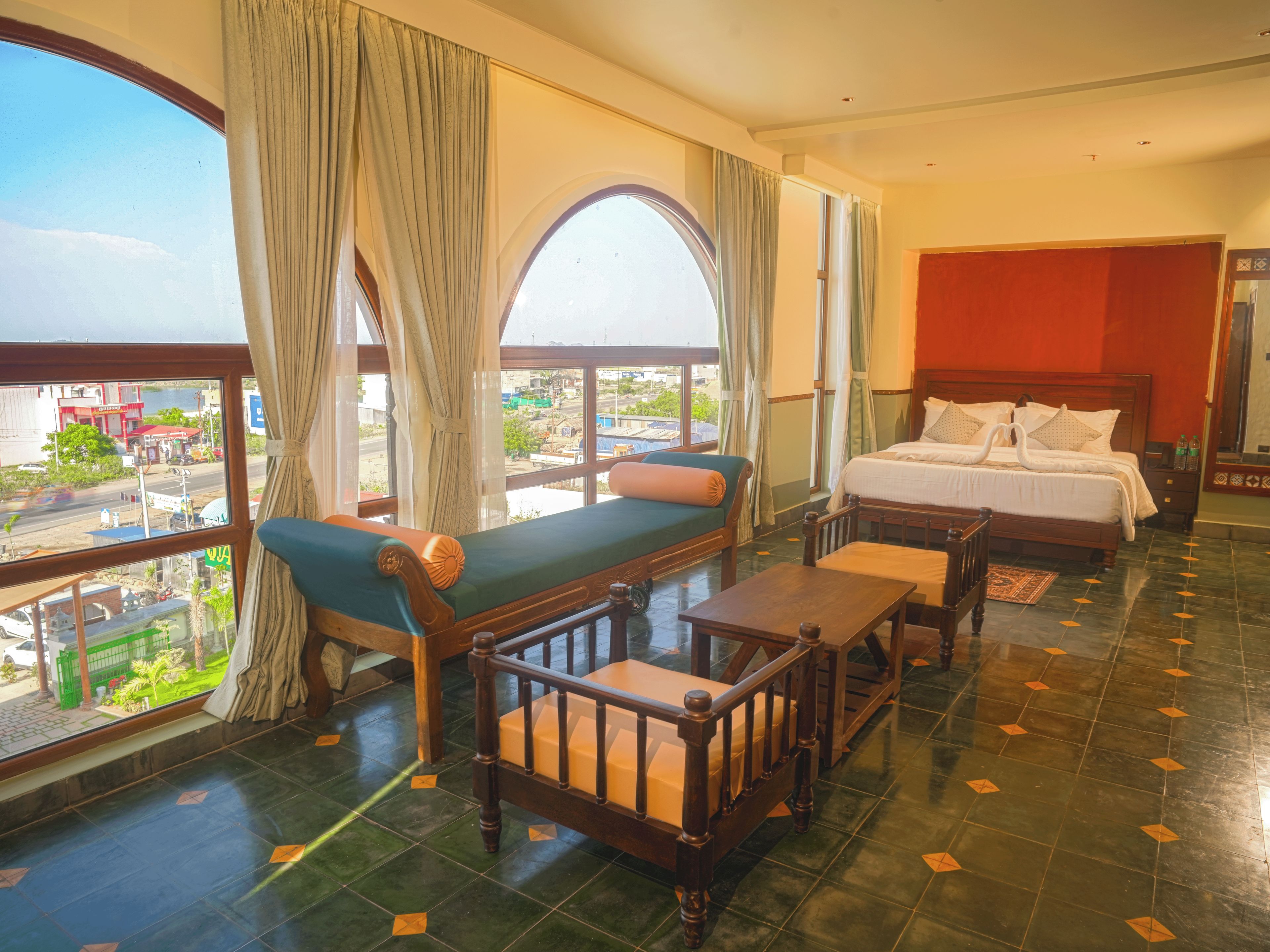 Een hotelkamer met een bed, een bank, een tafel en uitzicht op de stad.