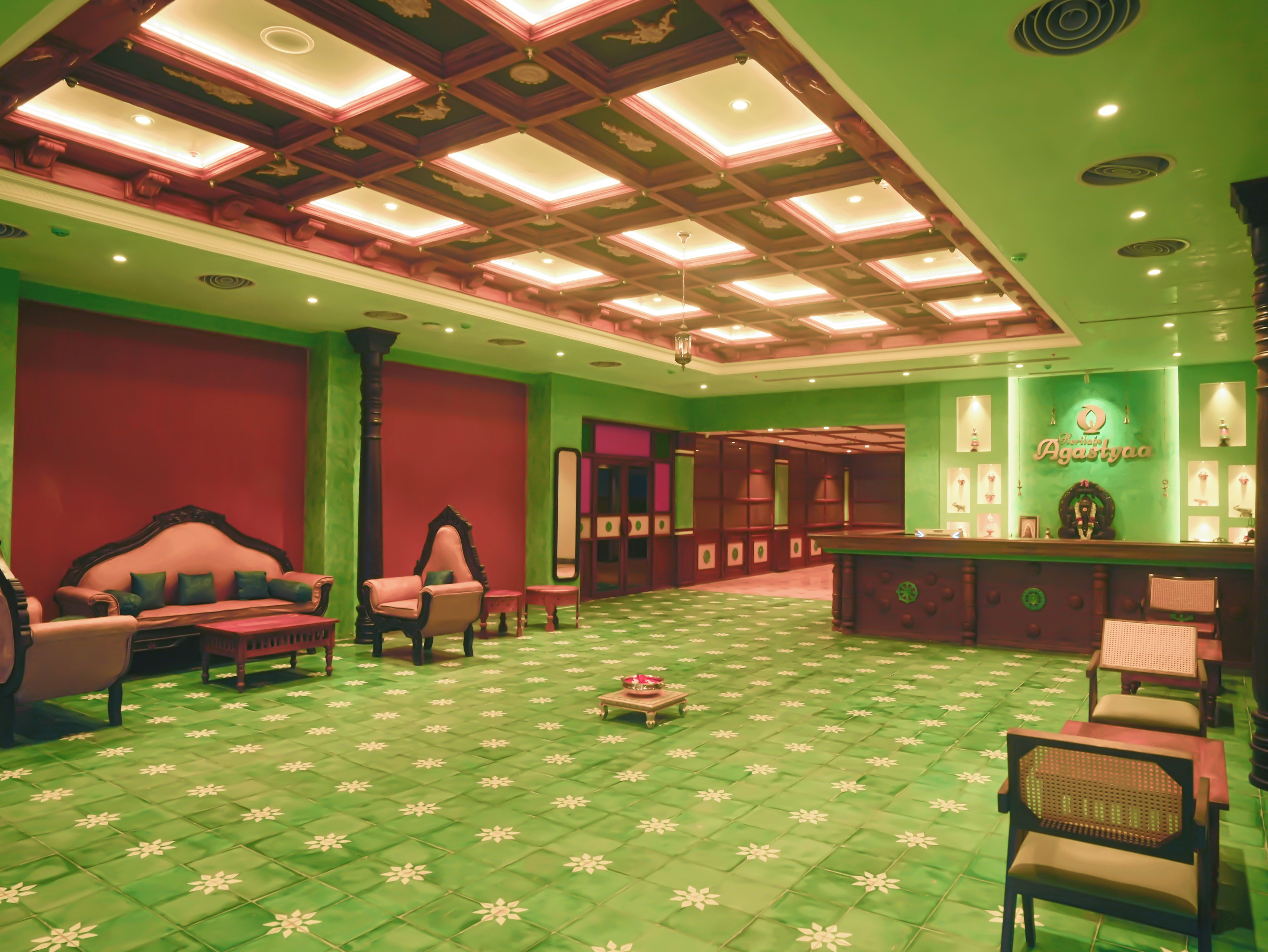 Vestíbulo de hotel con piso estampado verde, un mostrador de recepción y zonas de estar.