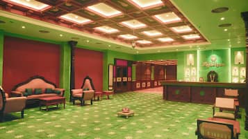 Vestíbulo de hotel con piso estampado verde, un mostrador de recepción y zonas de estar.