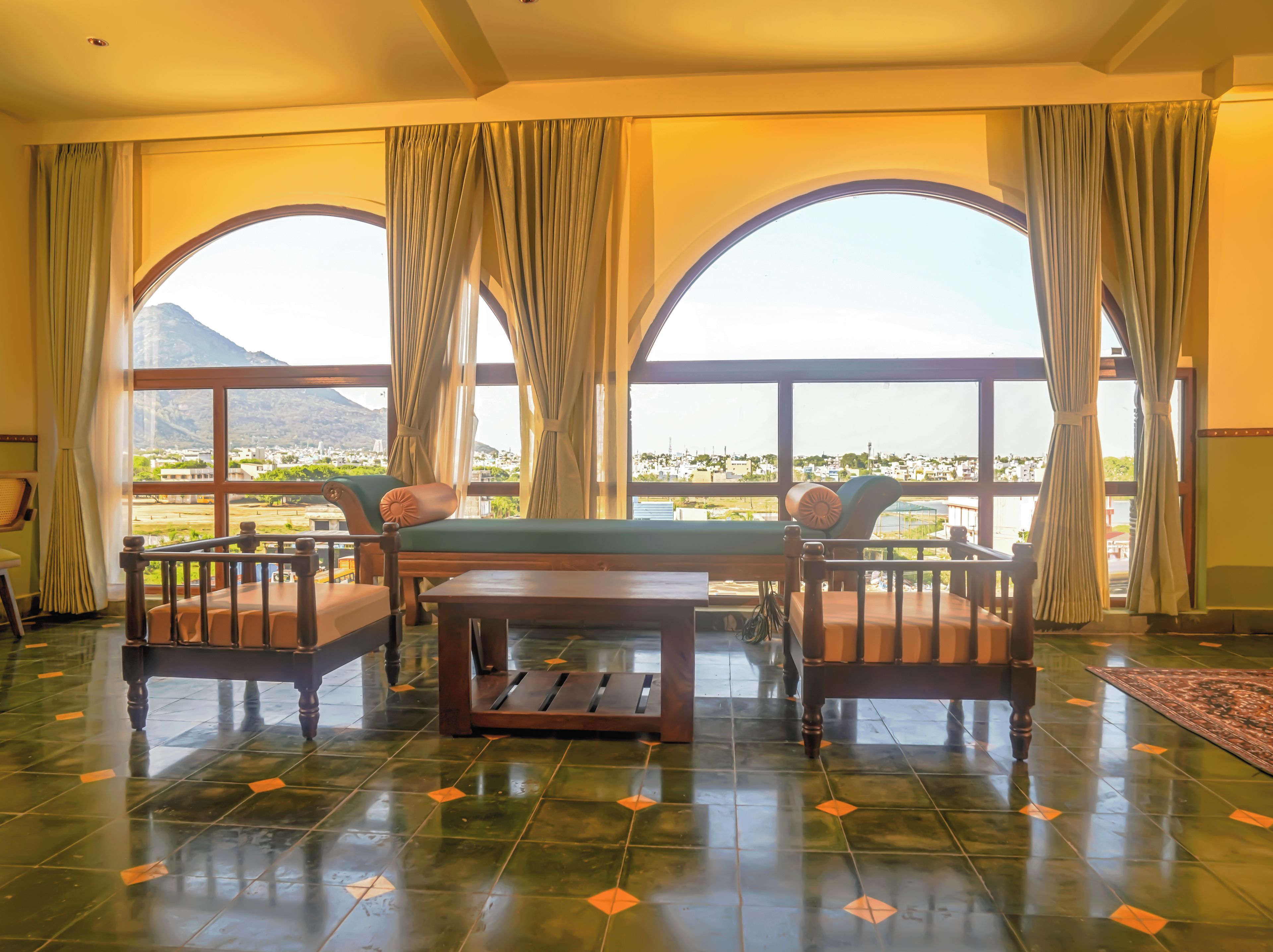 Una habitación con vistas a un paisaje montañoso a través de amplios ventanales, una mesa de madera y un sofá.