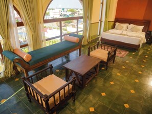 A hotel room with a large window, a bed, a bench, and a table. - Heritage Agastyaa (Tiruvannamalai)