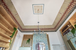 A room with a high ceiling, wooden beams, a chandelier, and a decorative mirror. - Stanze Letterarie – 'Rosa Balistreri' (Catania)