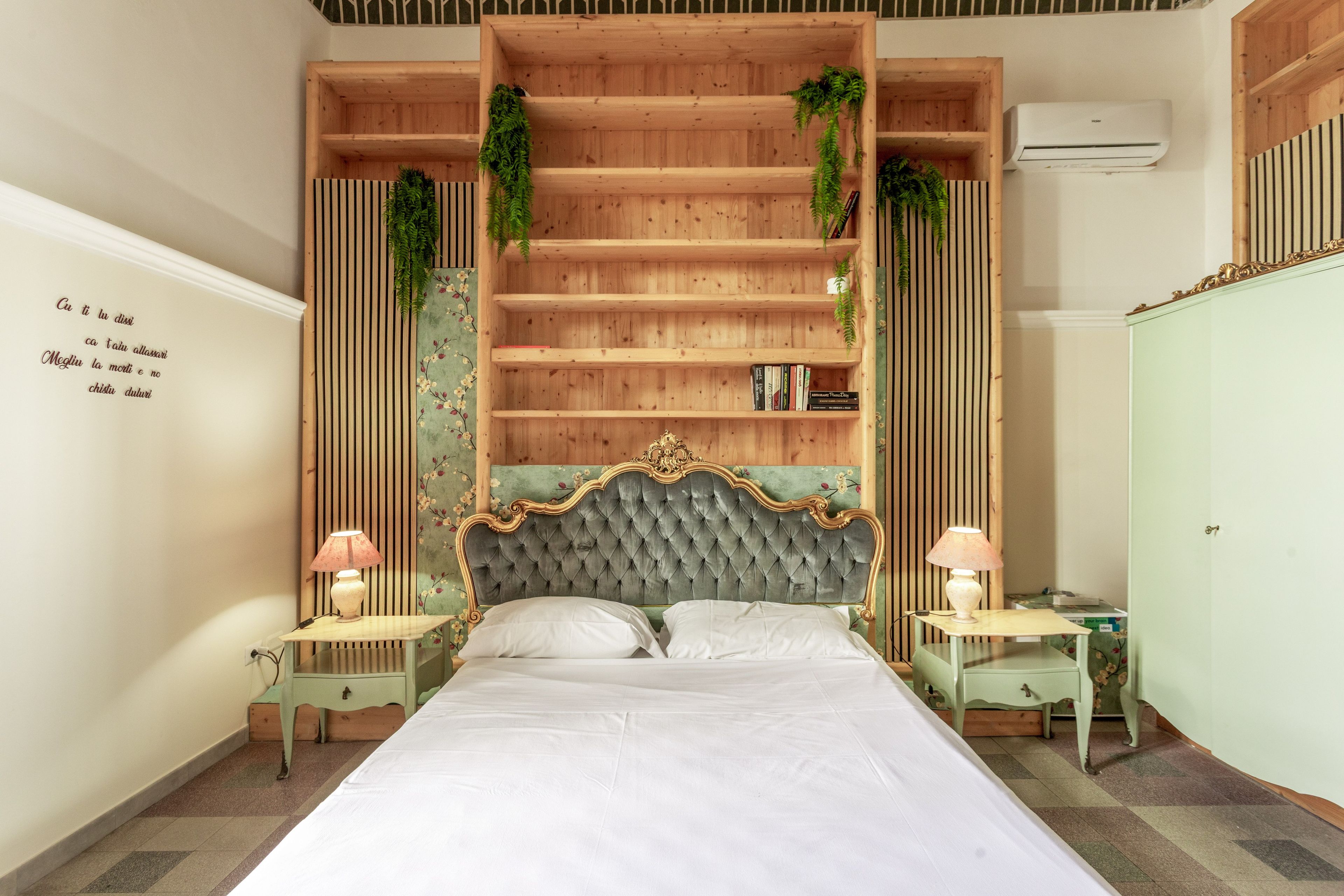 Een slaapkamer met een groot bed, houten planken, twee nachtkastjes met lampen en een airconditioning.