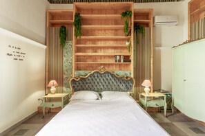 Quarto com uma cama grande, estantes de madeira, duas mesas de cabeceira com luminárias e um aparelho de ar condicionado.