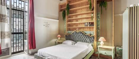 A bedroom with a bed, bedside tables, a chandelier, a window with curtains, and a wall with a decorative pattern.