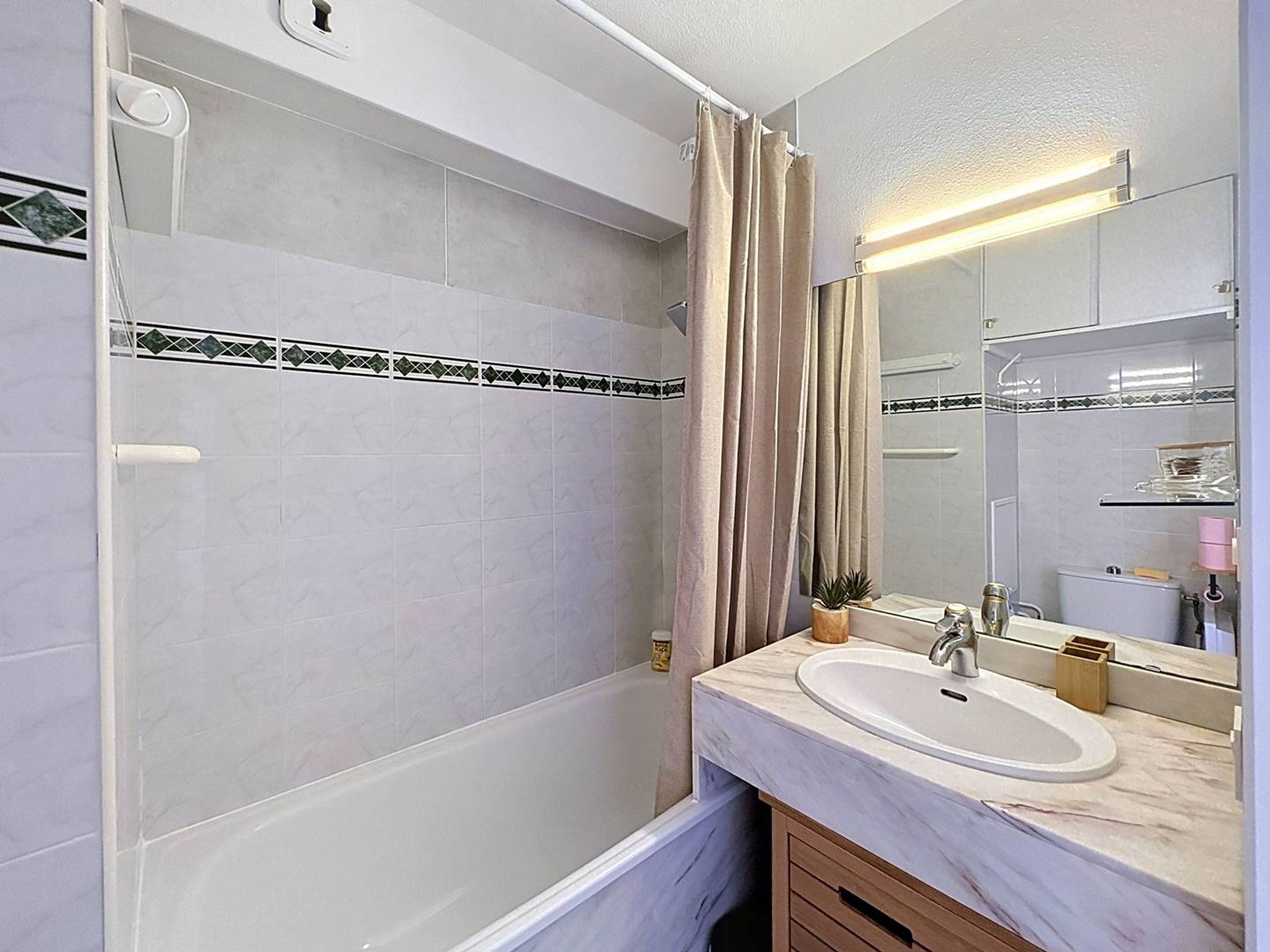 Ein Badezimmer mit Badewanne, Waschbecken, Spiegel und Duschvorhang.