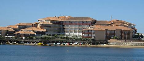 Un hotel costero con varias edificaciones, una playa y embarcaciones.