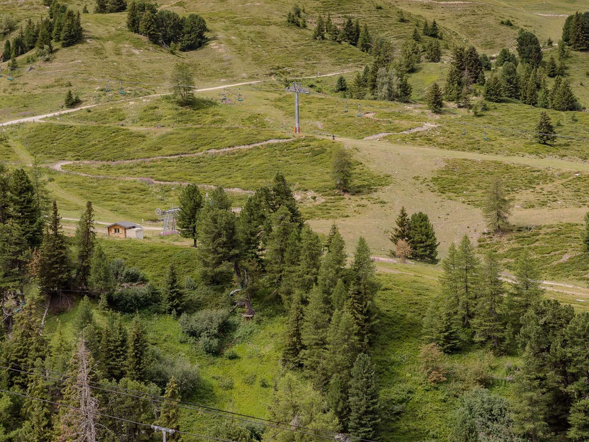 Un paysage montagneux avec une petite cabane et une éolienne.