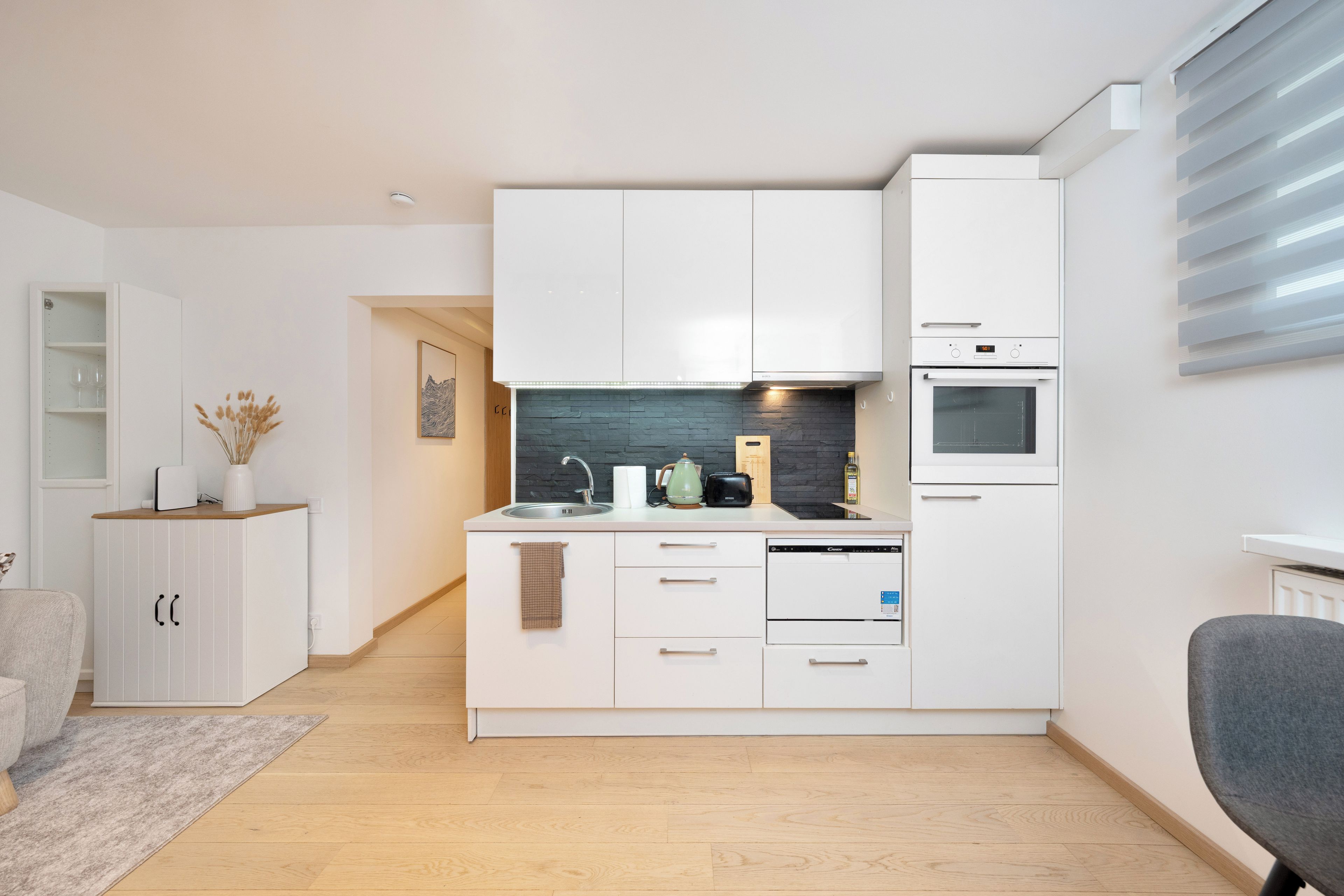A modern kitchen with white cabinetry, a built-in oven, and a microwave.