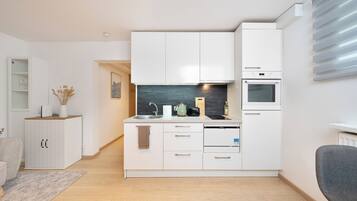A modern kitchen with white cabinetry, a built-in oven, and a microwave.