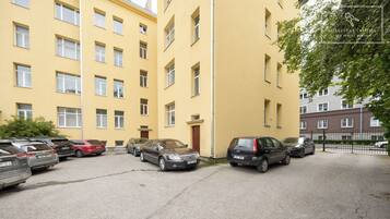 Ein Parkplatz mit mehreren Autos vor einem gelben Gebäude mit vielen Fenstern.