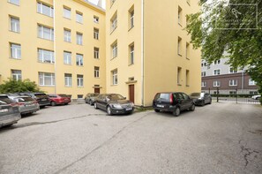 En parkeringsplads med flere biler parkeret foran en gul bygning med mange vinduer.