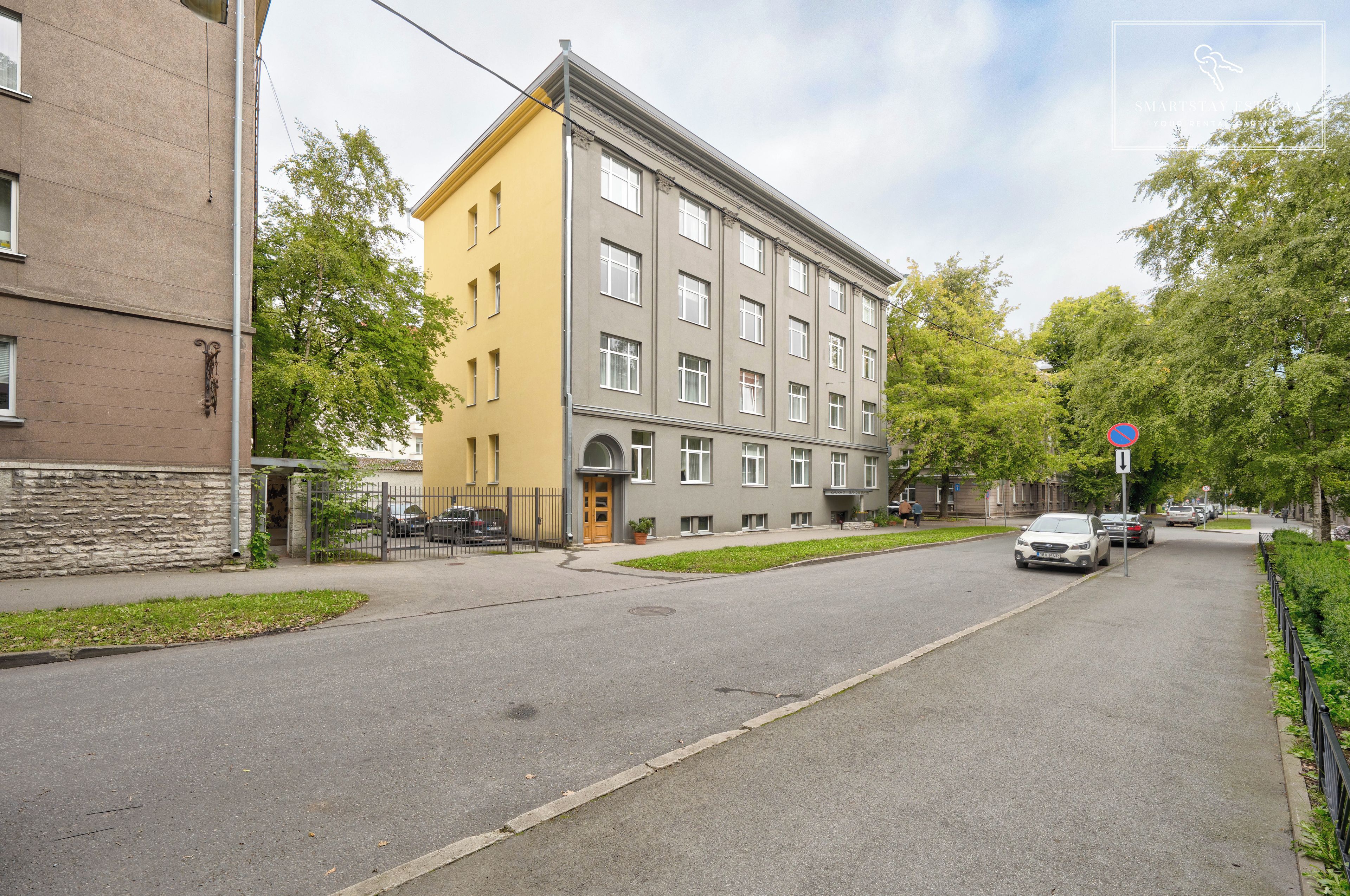 A street view with a two-story building, a no parking sign, and a pedestrian pathway.