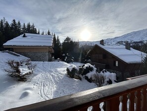 A snow-covered landscape with a wooden cabin and a stone building, both with snow on their roofs. - 3-Room Apartment in Méribel - Sleeps 6 (Méribel)
