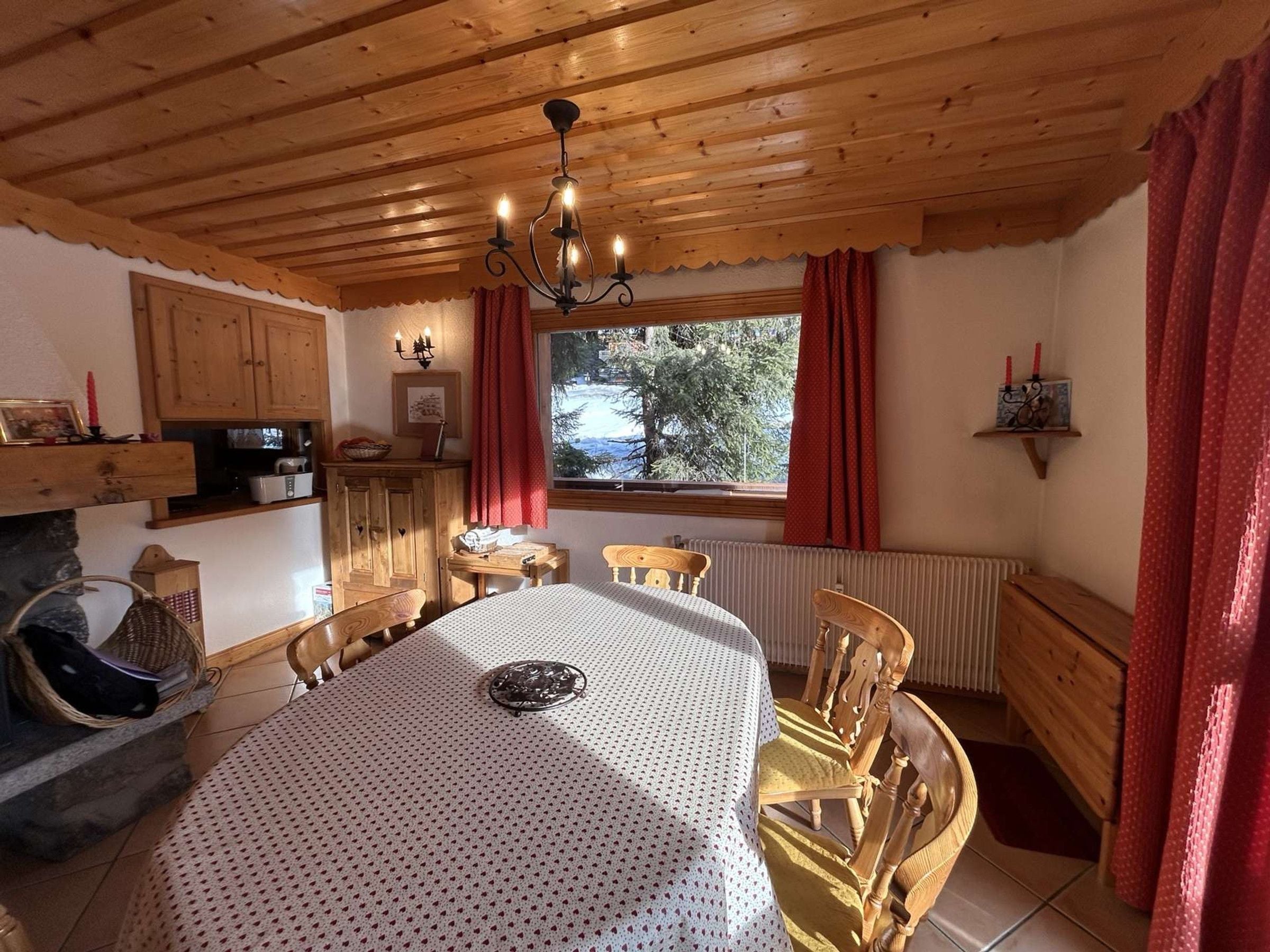 A cozy dining area with a wooden ceiling, a table with a patterned tablecloth, and chairs.