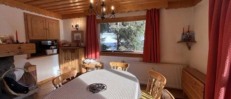 A cozy dining area with a wooden ceiling, a table with a patterned tablecloth, and chairs.
