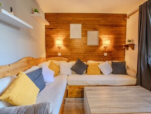 Ein gemütliches Zimmer mit Holzwand, einer Couch, einem kleinen Tisch und Wandleuchten.