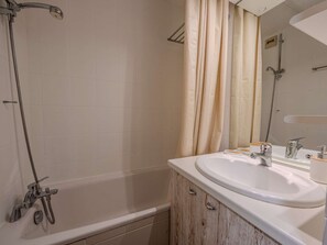 Ein Badezimmer mit einer Badewanne, einer Dusche, einem Waschbecken und einem Spiegel.