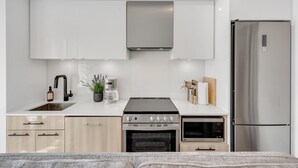 A modern kitchen with a stainless steel stove, oven, and refrigerator, white cabinetry, and a sink with a faucet. - StayToronto - Work-Friendly 1BR Suite Steps to Eaton Centre (Toronto)