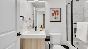 A modern bathroom with a white sink, toilet, and shower. A framed picture of Toronto is on the wall. - StayToronto - Work-Friendly 1BR Suite Steps to Eaton Centre (Toronto)