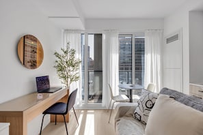 Un espace de vie moderne comprenant un bureau, un ordinateur portable et un coin salon.
